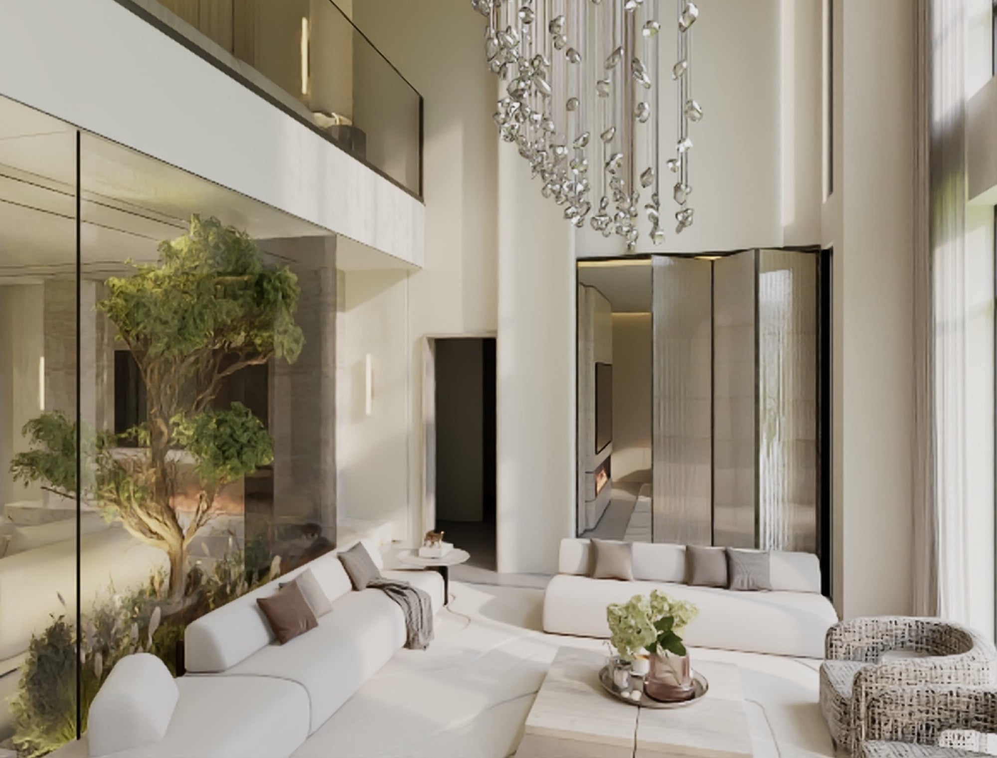 A double-height room with a glass-drop chandelier, white sofas and a courtyard tree behind full-height glazing, designed by Radwa Interiors.