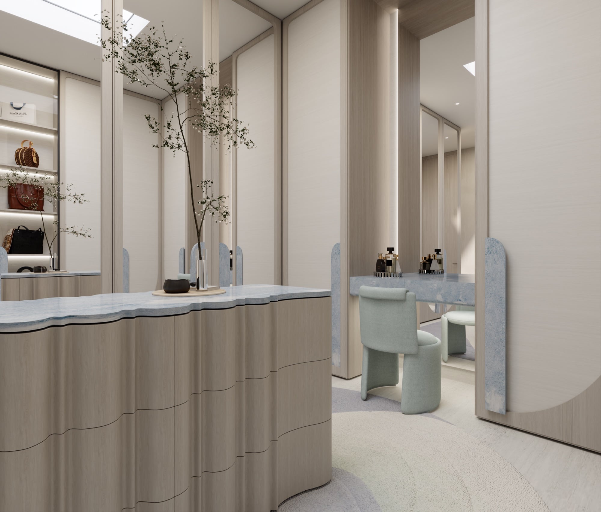 A dressing room island in ribbed timber with a pale blue stone top, beside a mint upholstered chair at a mirrored vanity, designed by Radwa Interiors.