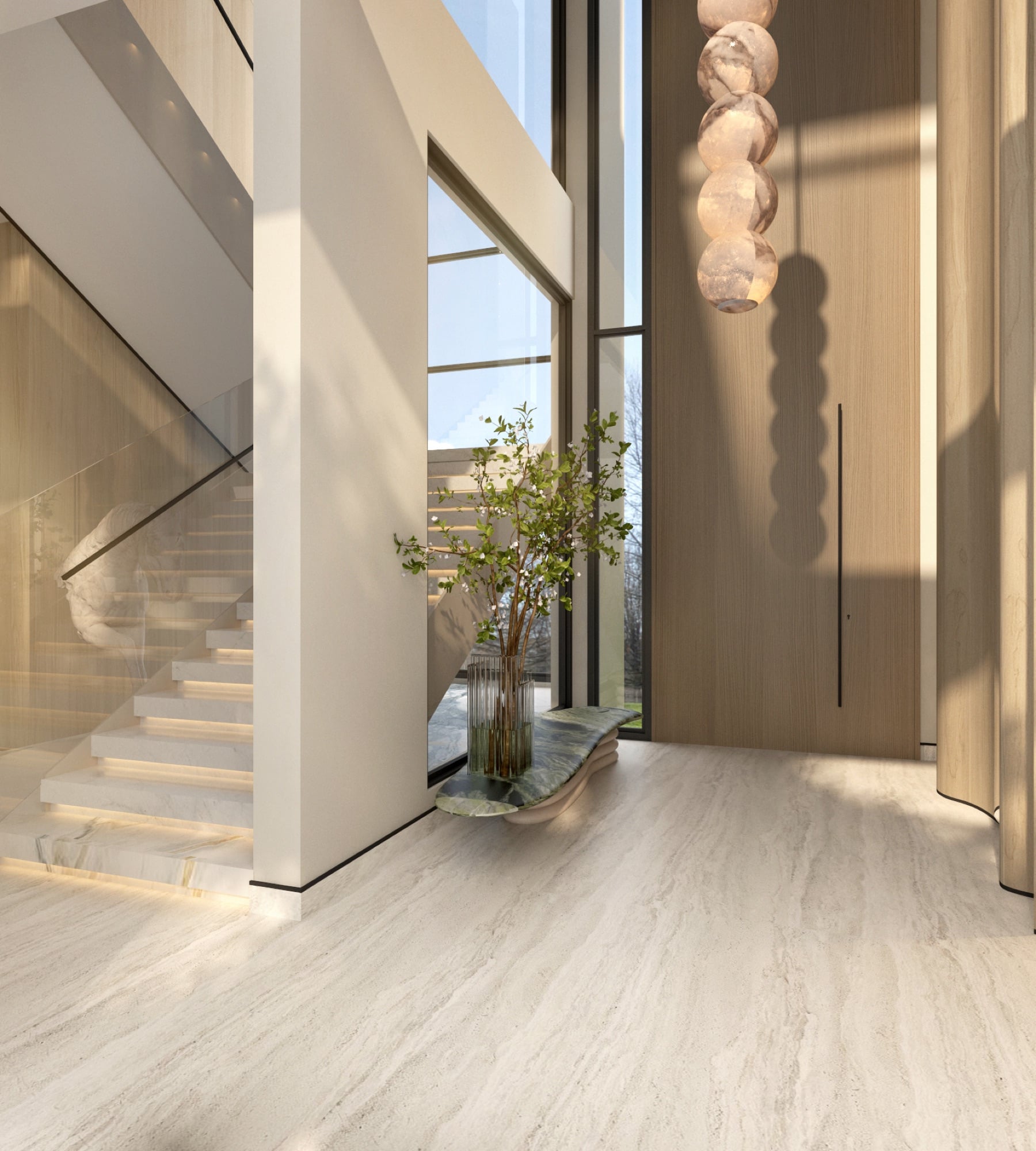 An entrance hall with a stacked alabaster sphere pendant, a slim tree on a green stone plinth and a stone staircase, designed by Radwa Interiors.