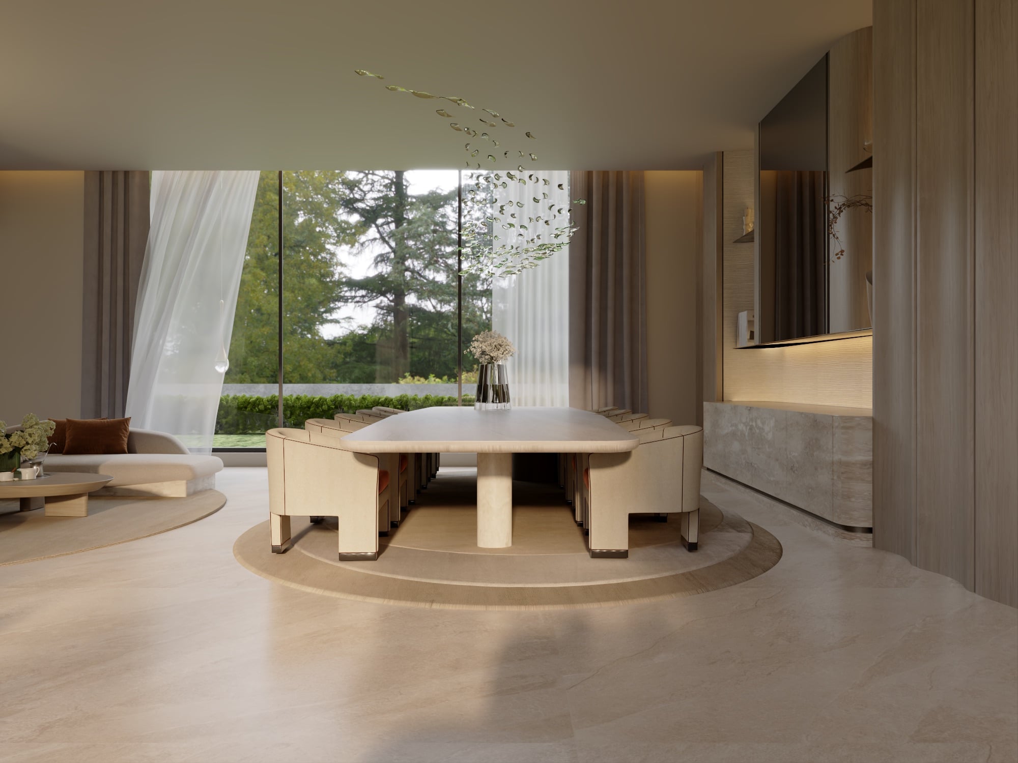 A dining table with cream chairs on a round plinth, below a scattered leaf mobile, beside a curved sofa and garden glazing, designed by Radwa Interiors.