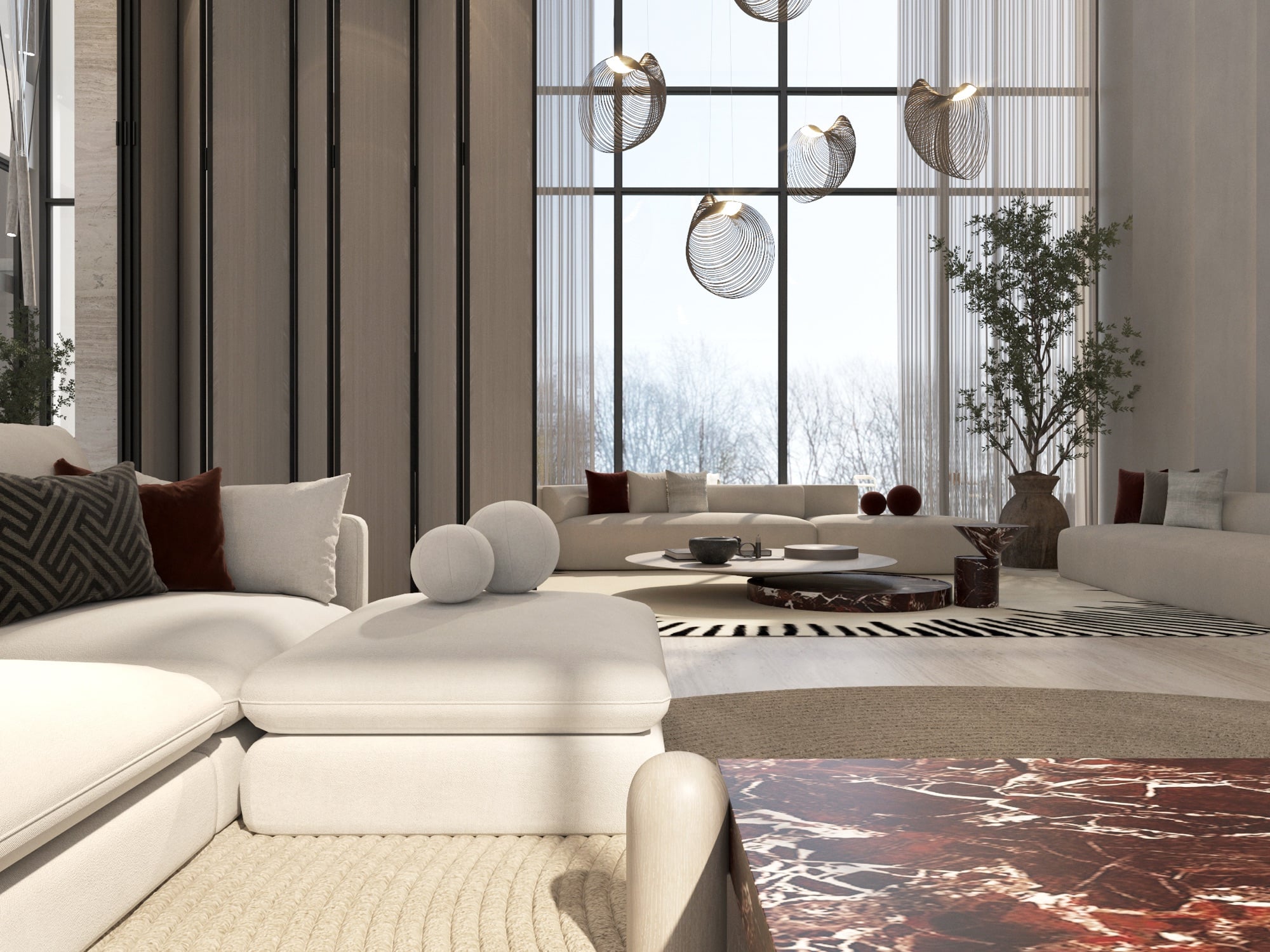 A double-height living room with cream modular seating, a red-veined marble table and woven globe pendants against full-height windows, designed by Radwa Interiors.