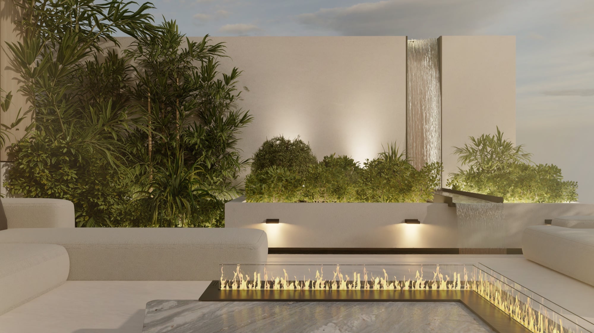A fire table set into a stone terrace at dusk, with a water blade and lit planting behind, designed by Radwa Interiors.