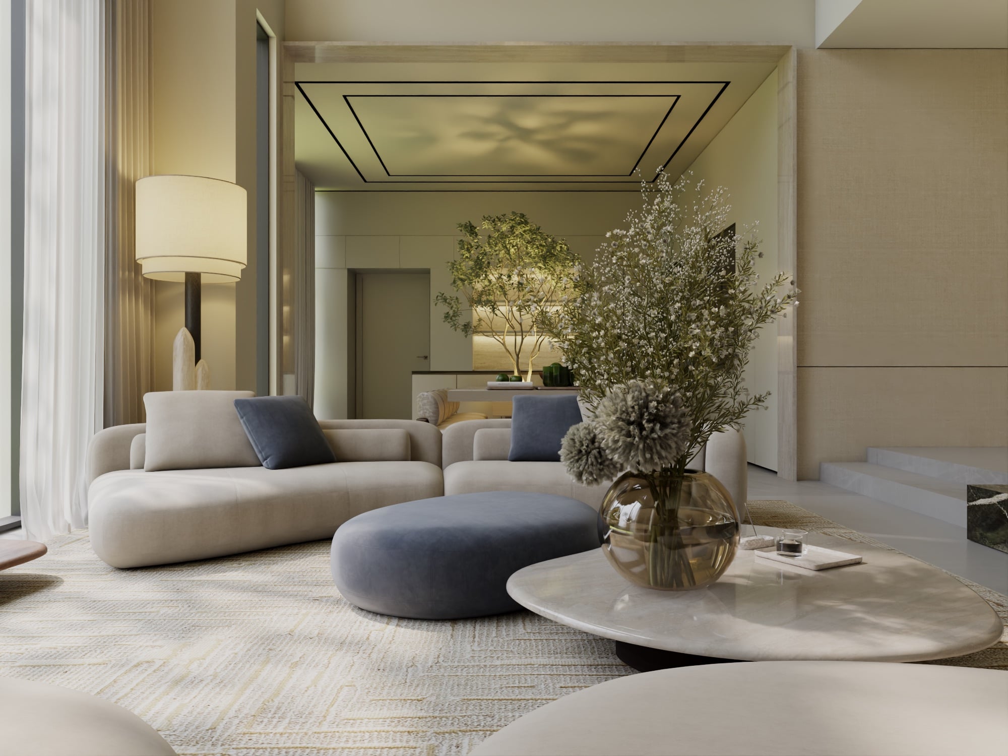 A living room with a blue-grey ottoman and a bronze glass vase of dried blooms, opening to a courtyard tree, designed by Radwa Interiors.